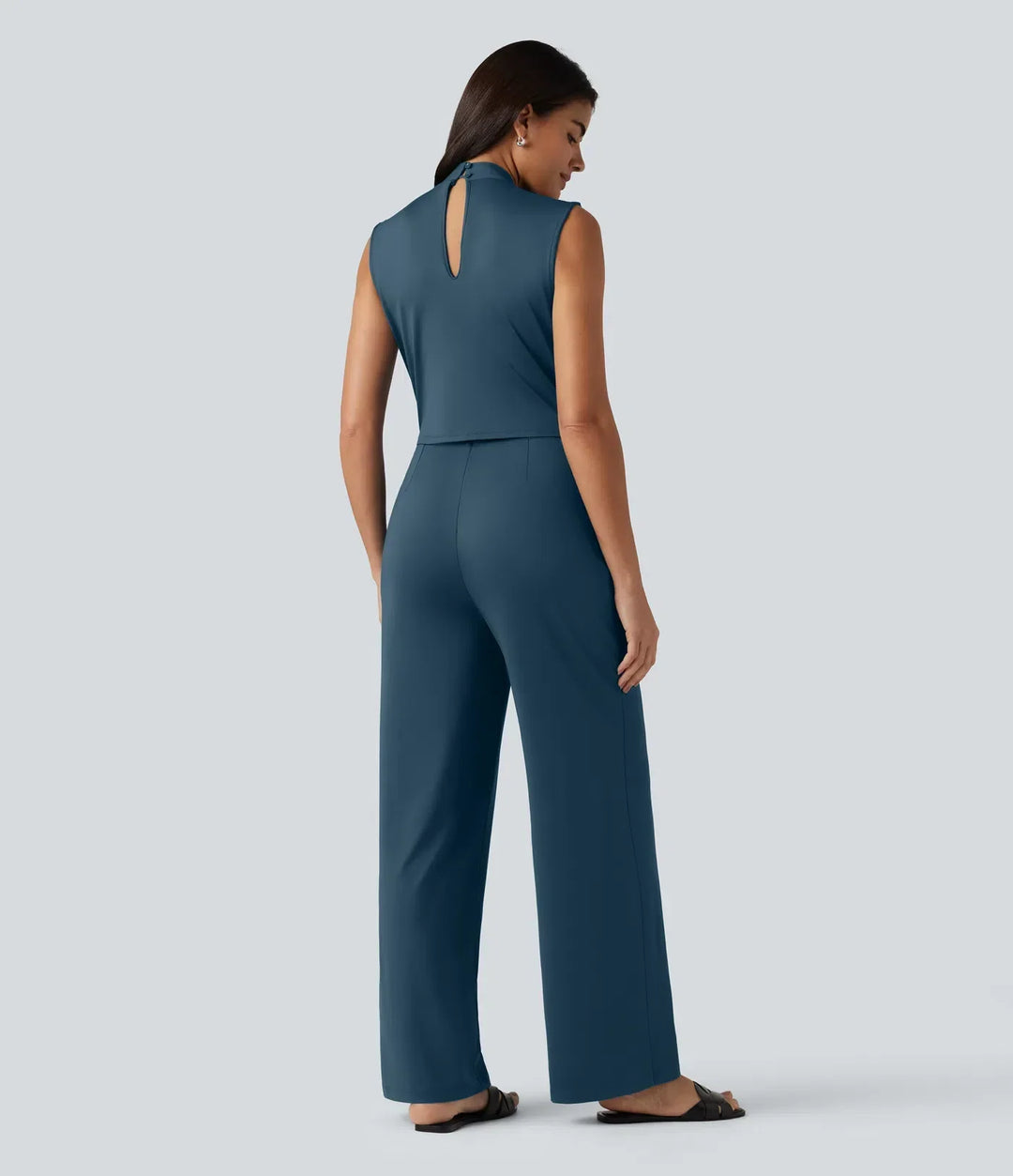 Baksidan av den blå damjumpsuiten med knappdetalj i nacken
