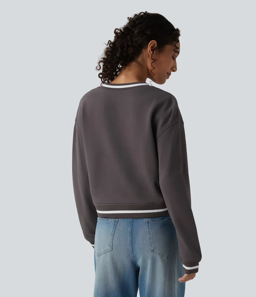 Kvinna i mörkgrå sweatshirt med V-ringning bakifrån