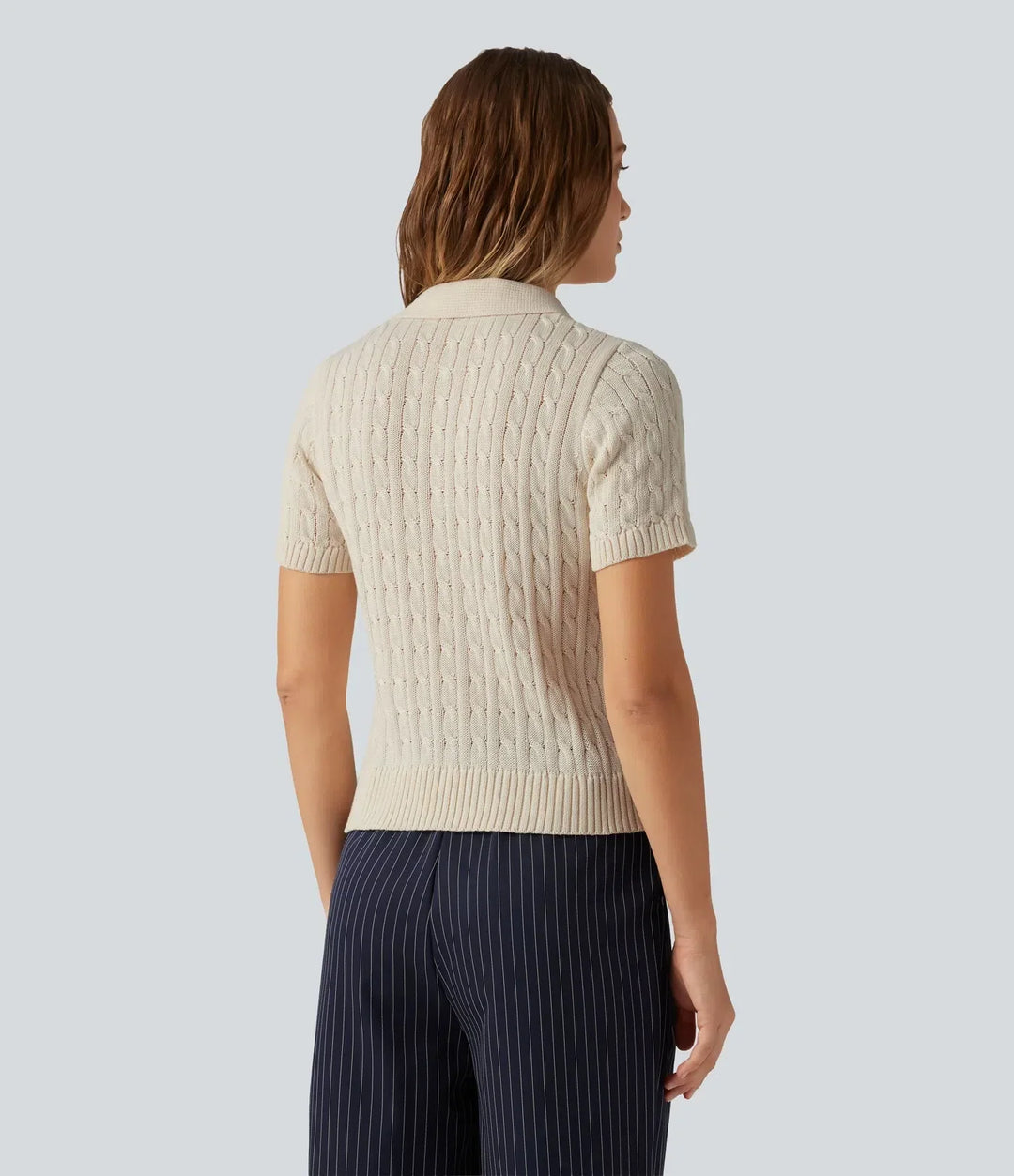 Kvinna som bär beige kortärmad kabelstickad polotröja bakifrån
