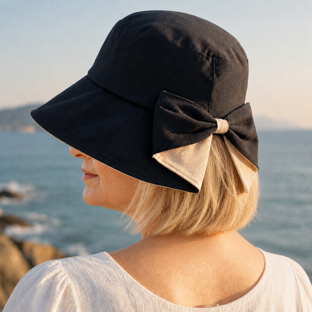 Svart solhatt för dam med elegant rosett bakifrån sedd vid havet