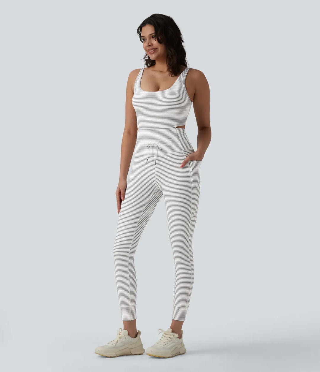 Helbild framifrån av dam i randig yoga jumpsuit med träningsskor