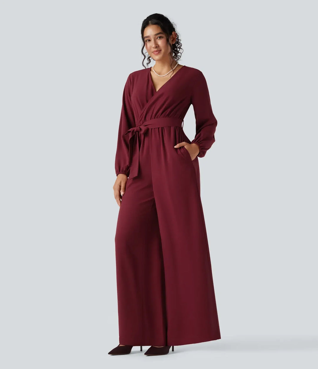 Modell som visar fickorna på den vinröda festjumpsuiten