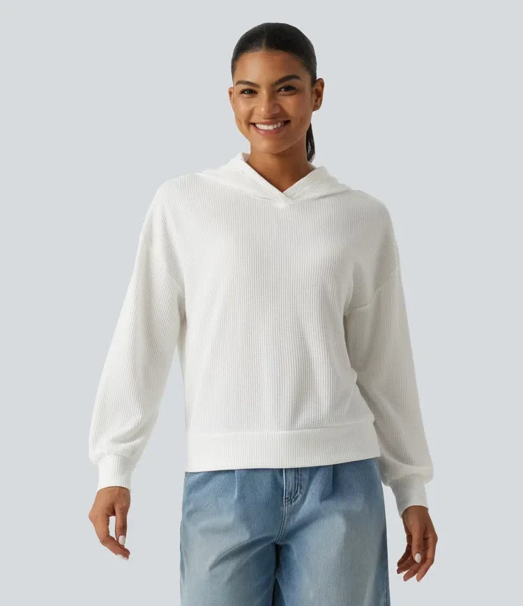Kvinna som bär en vit sweatshirt med huva och våffelstruktur framifrån