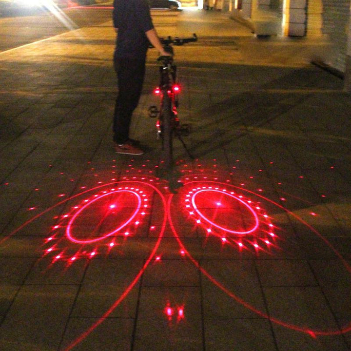 Cyklist som står bredvid en cykel med aktiverade laserljus på marken