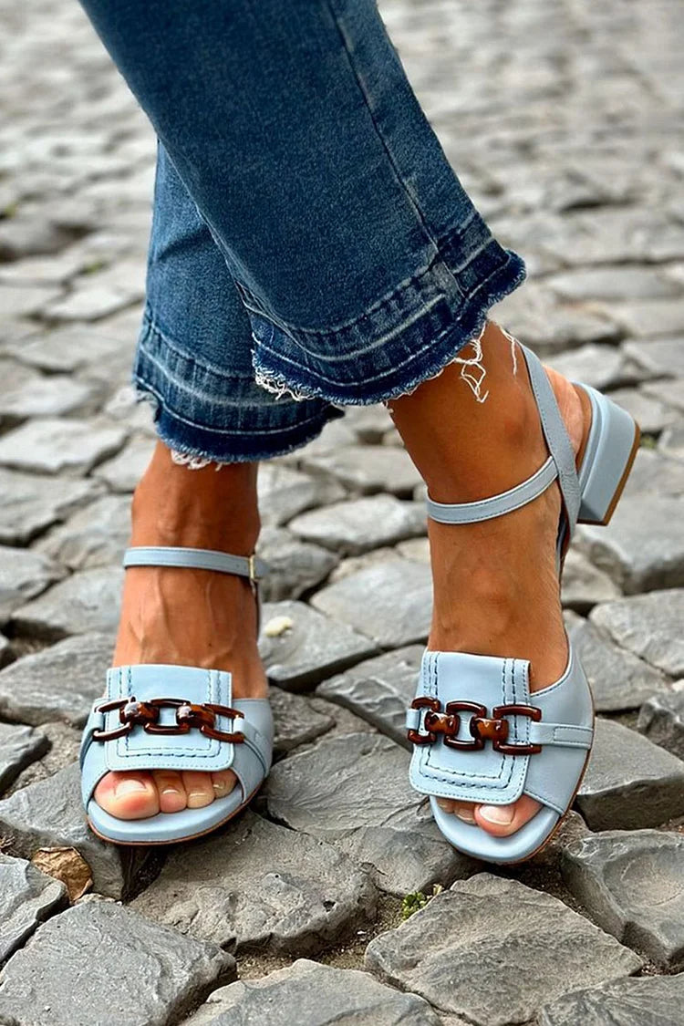 Närbild på dam sandaler med blockklack och kedjedetalj utomhus