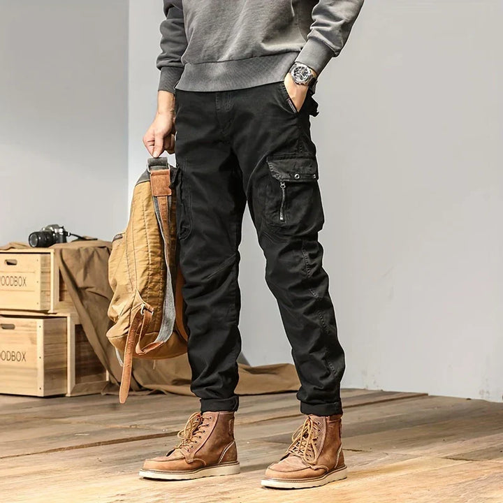Man i svarta cargo joggers med praktiska fickor och stilren tröja
