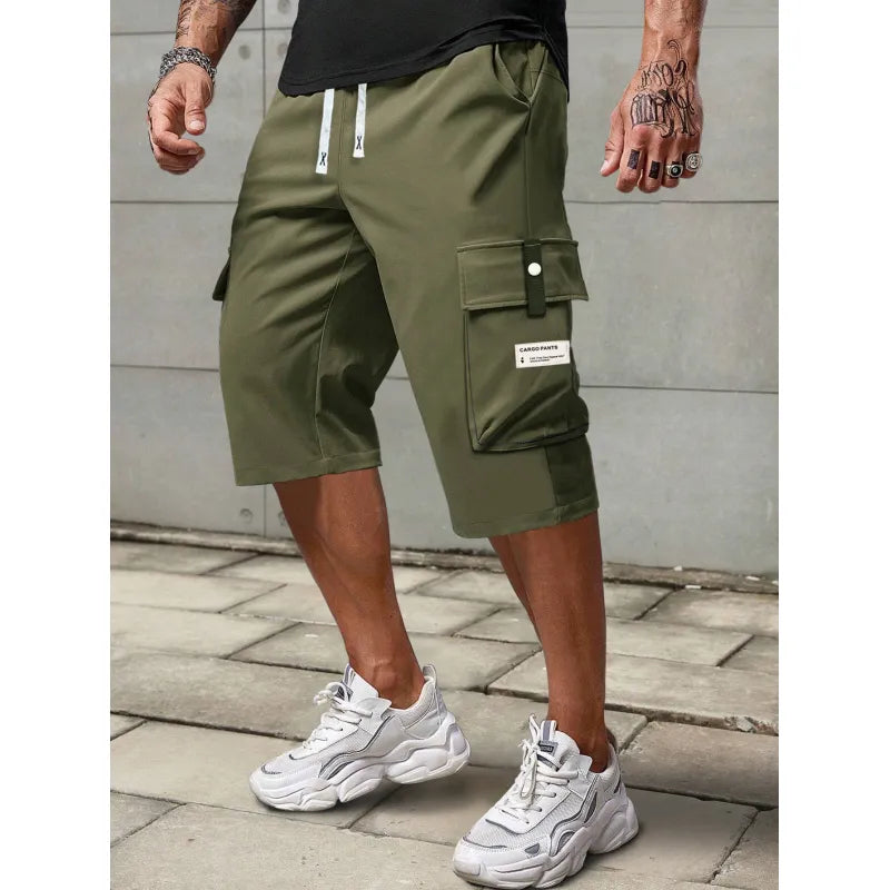 Man i militärgröna cargoshorts med sidofickor och vita sneakers