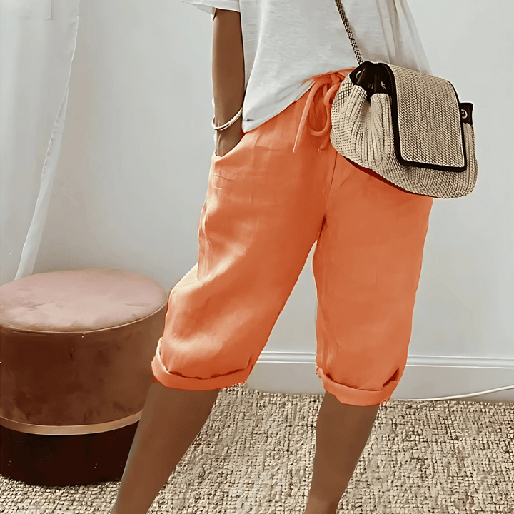 Kvinna i orange knälånga haremshorts med matchande väska
