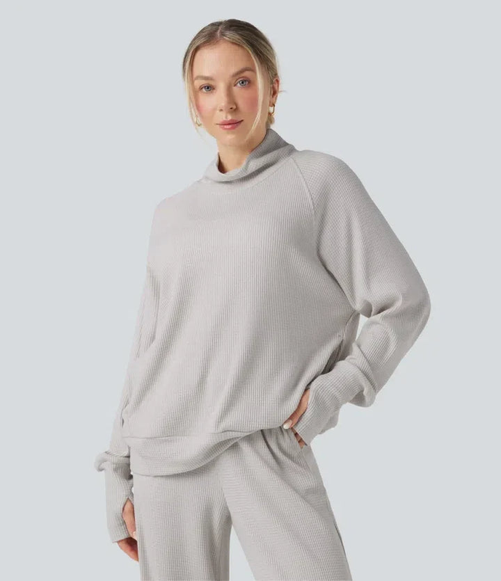 Kvinna som bär grå oversized sweatshirt med hög krage och tumhål framifrån