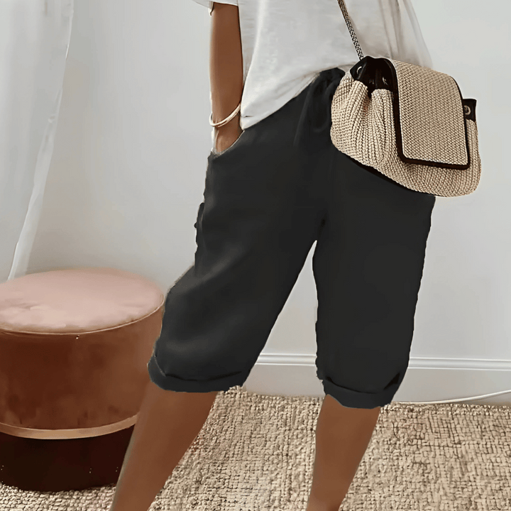 Kvinna i svarta knälånga haremshorts med sidfickor