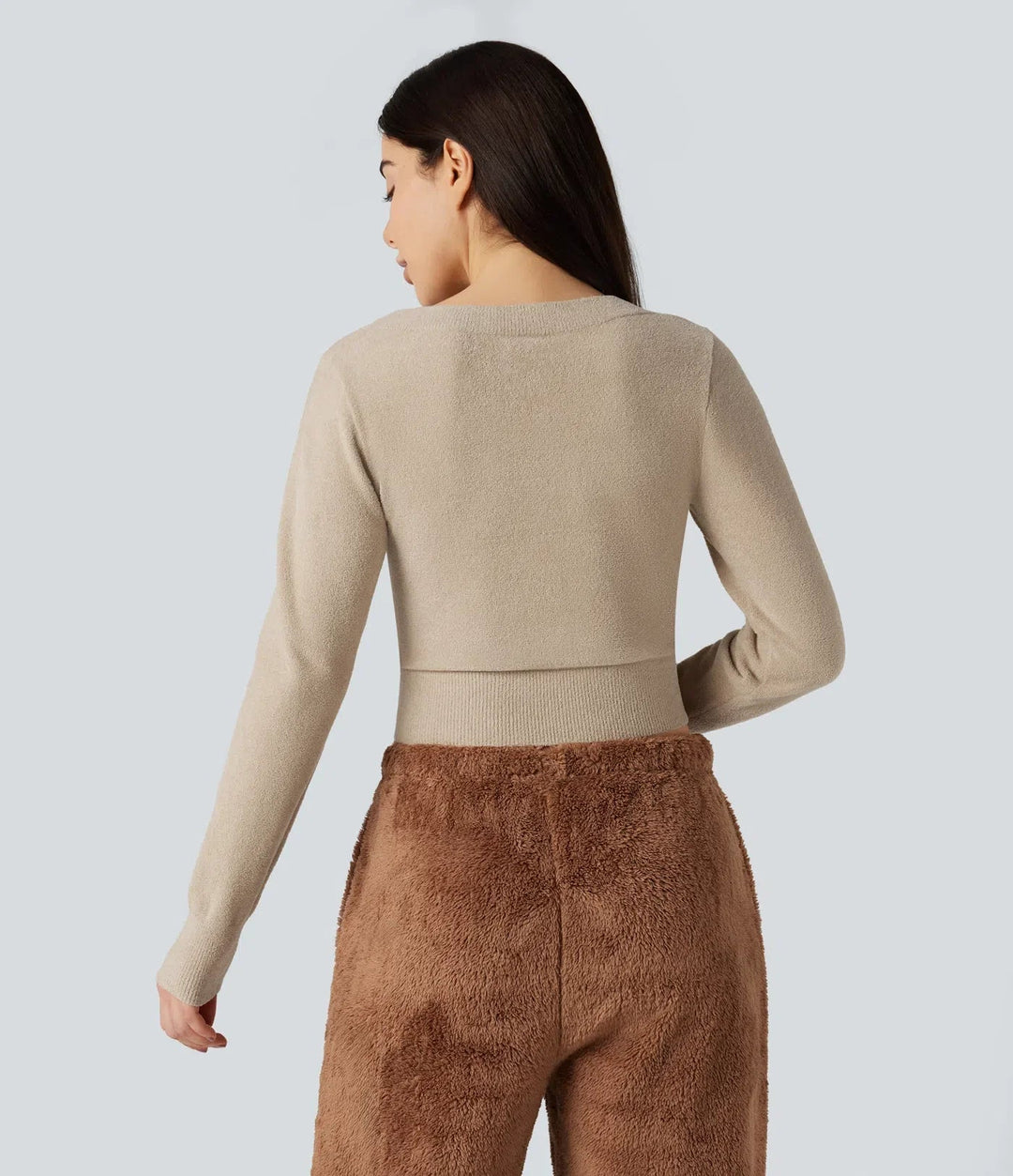 Kvinna i beige u-ringad långärmad croppad tröja bakifrån
