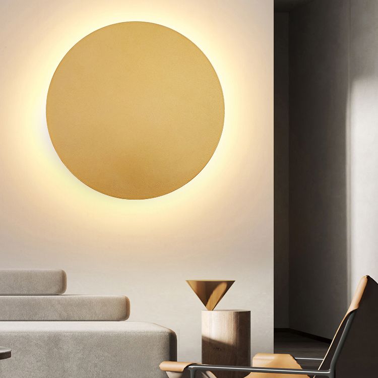 Modern rund guld-vägglampa monterad i ett elegant vardagsrum