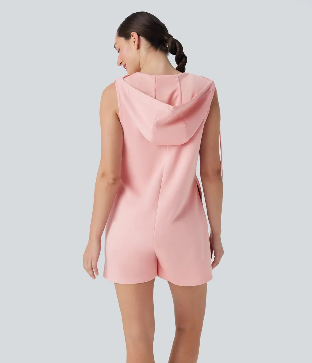 Kvinna i rosa ärmlös jumpsuit med huva bakifrån