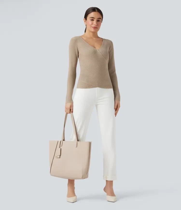 Kvinna som bär beige långärmad crossover-tröja och vita byxor med väska
