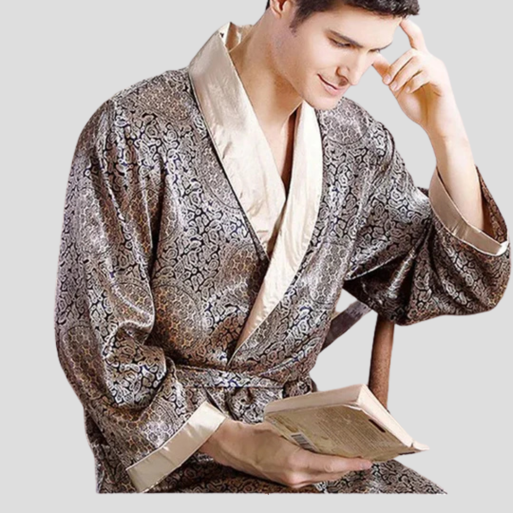 Närbild på man i mönstrad kimono badrock i satin som håller i en bok