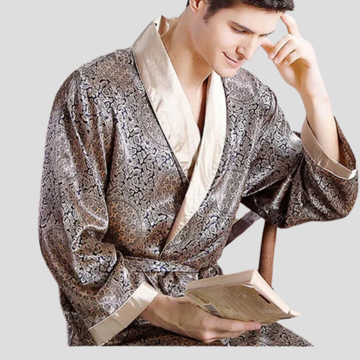 Närbild på man i mönstrad kimono badrock i satin som håller i en bok