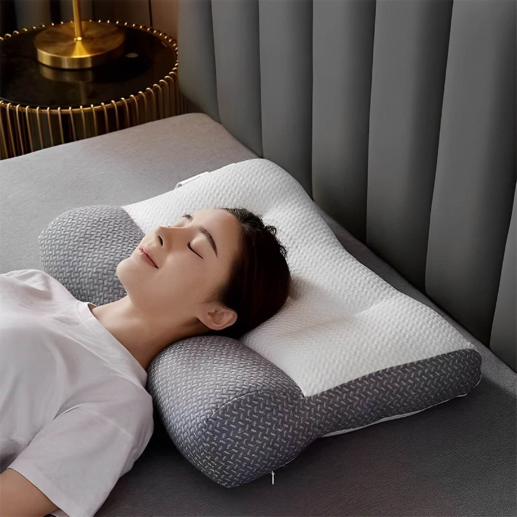 Kvinna som sover bekvämt på en grå ergonomisk nackkudde i sängen