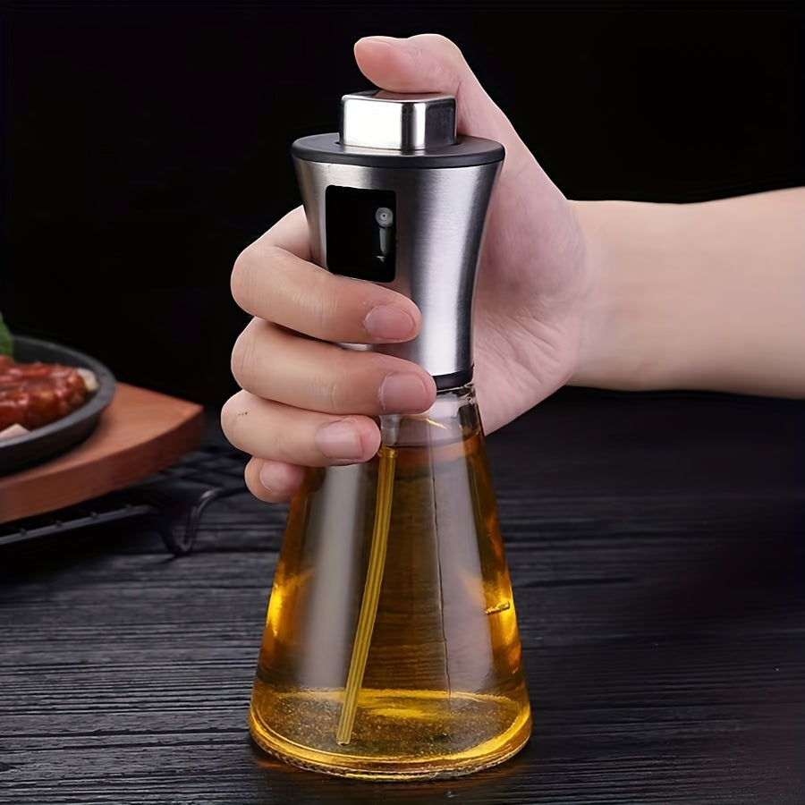 Hand som håller i en oljesprayflaska i rostfritt stål och glas