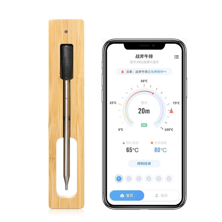 Trådlös smart kötttermometer med laddningsstation i bambu bredvid en mobiltelefon som visar appgränssnittet