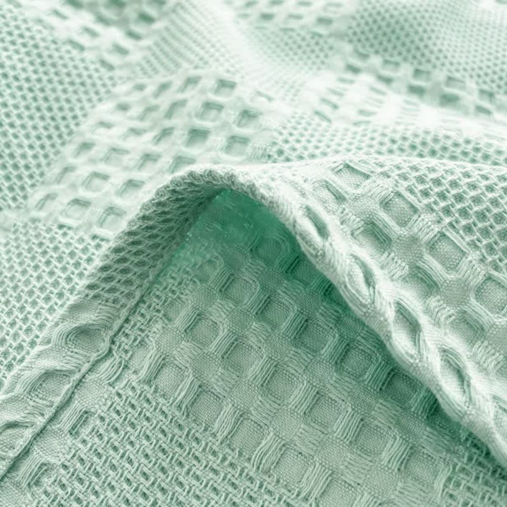 Stilren pläd i våfflad design draperad över en fåtölj i sovrummet