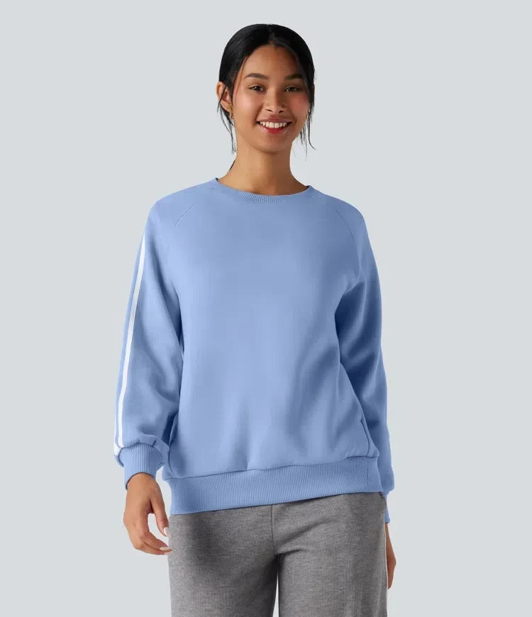 Kvinna som bser en ljusblå sweatshirt med vita sidoränder framifrån