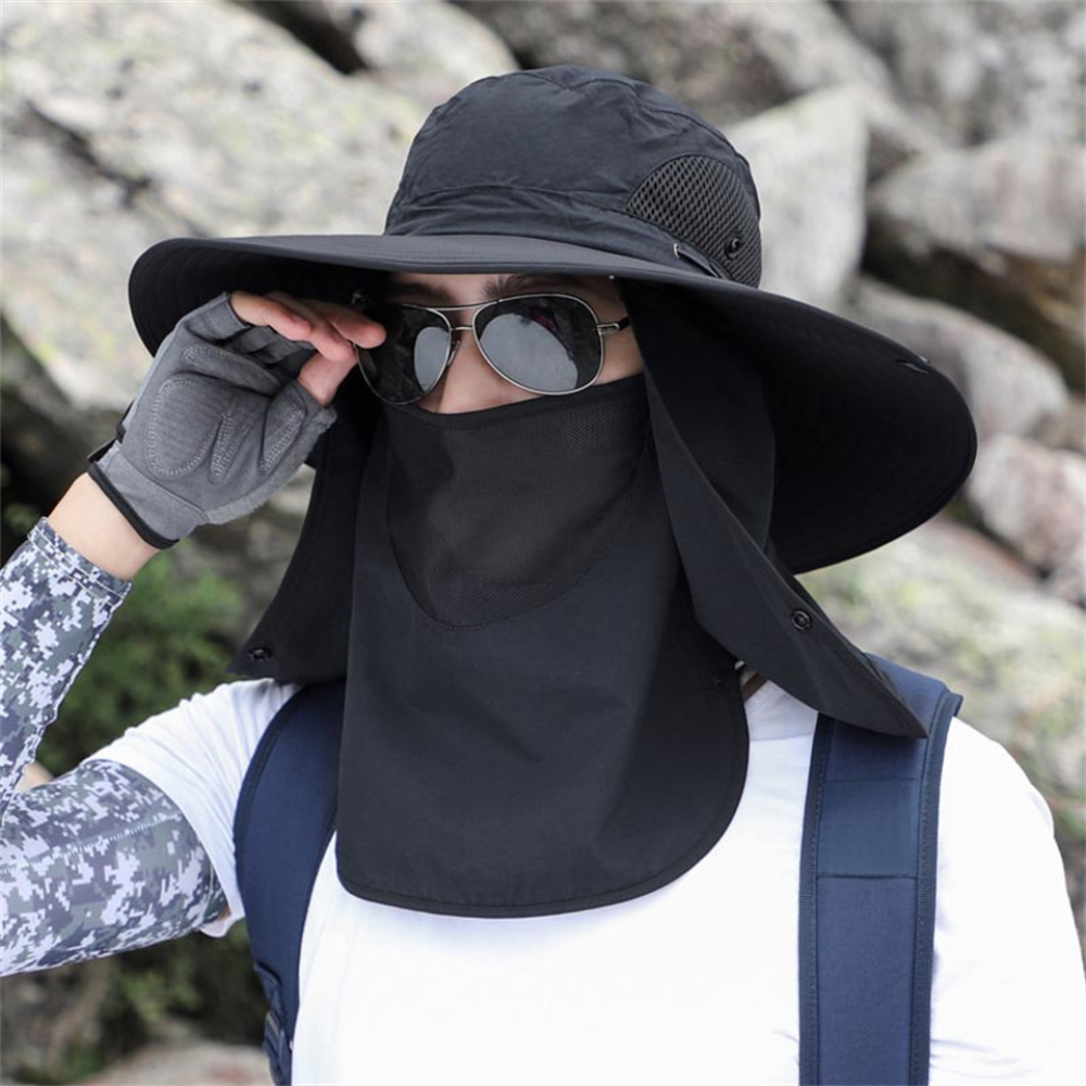 Person i svart solhatt med bred skärm vid klippor