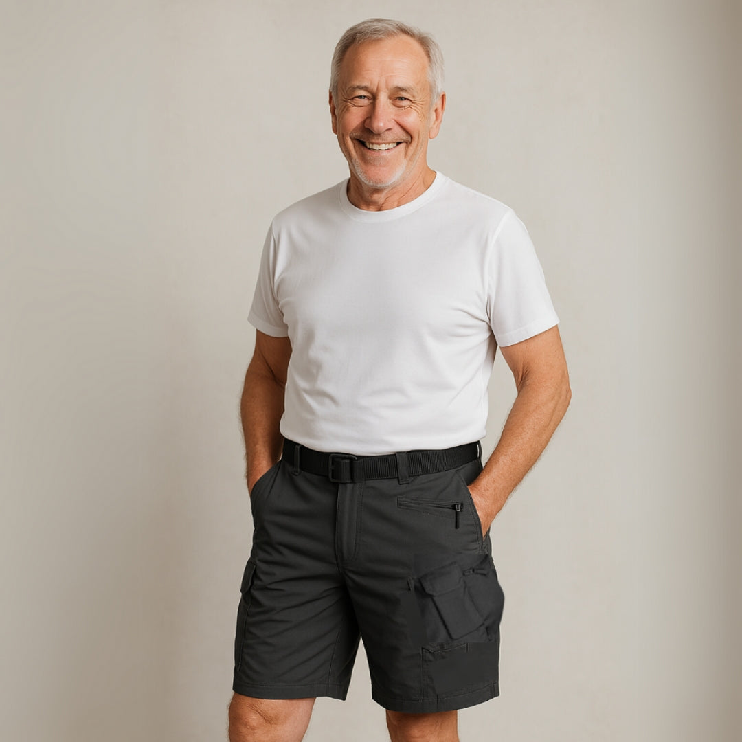 Äldre man som ler iklädd mörka cargo-shorts och vit t-shirt