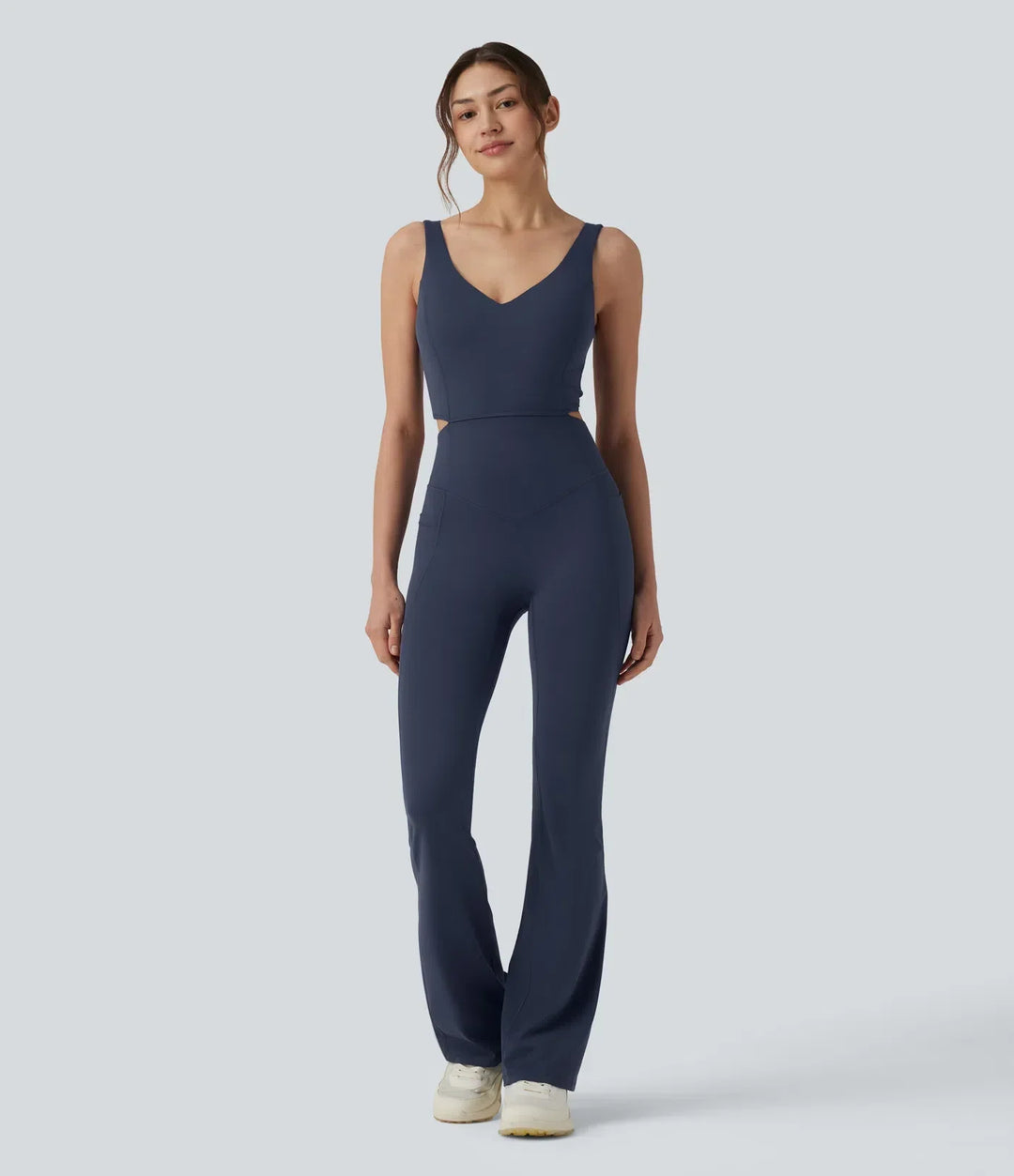 Modell i helfigur framifrån i blå träningsjumpsuit