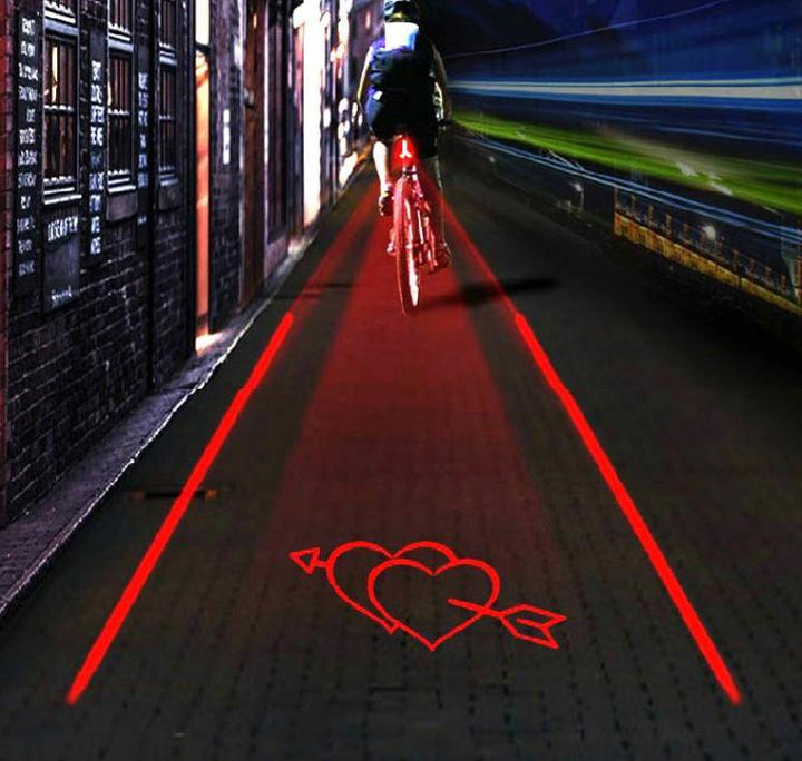Cykel med laserljus som projicerar en röd linje och ett hjärta på gatan