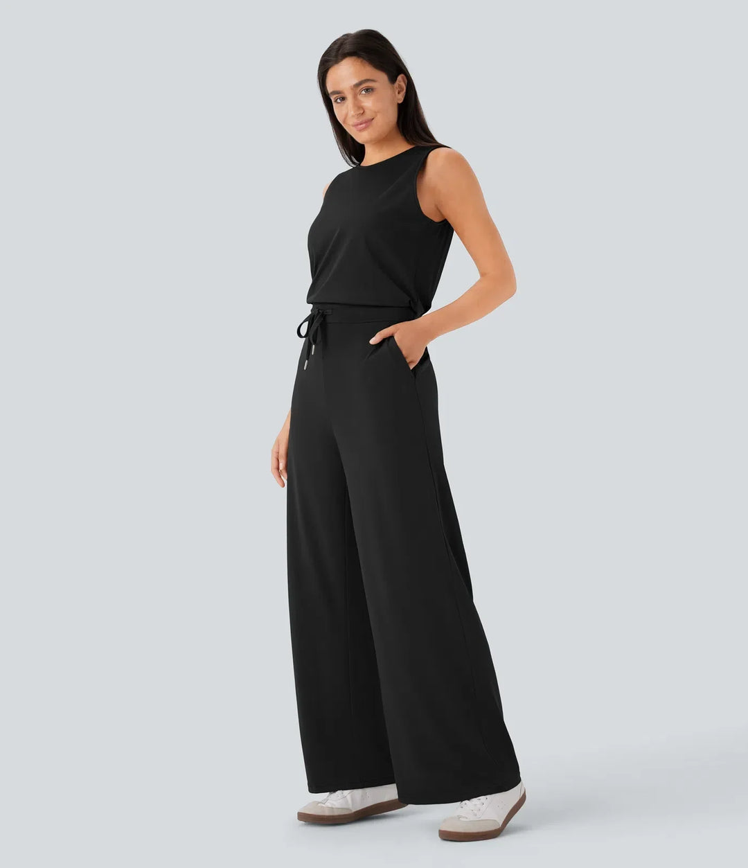 Sida av svart ärmlös jumpsuit med fickor och ledig passform