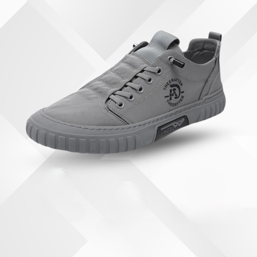Grå unisex-sneaker med snörning och mönstrad sula mot ljus bakgrund
