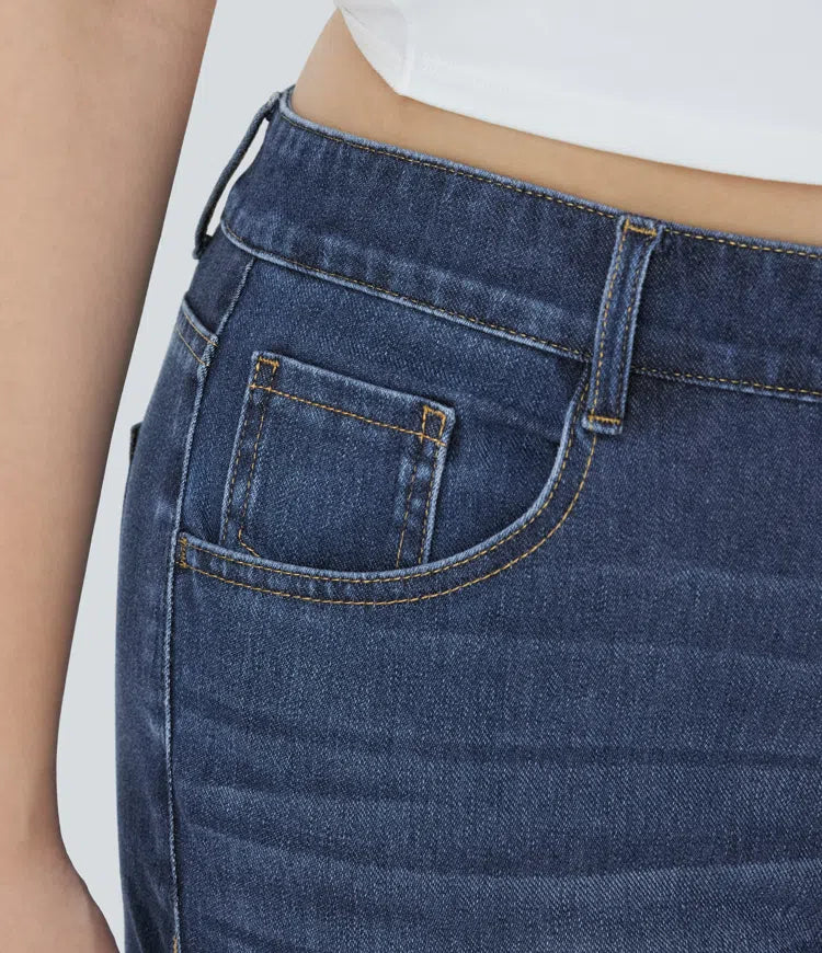 Närbild på knapp och gylf på blå damjeans med hög midja