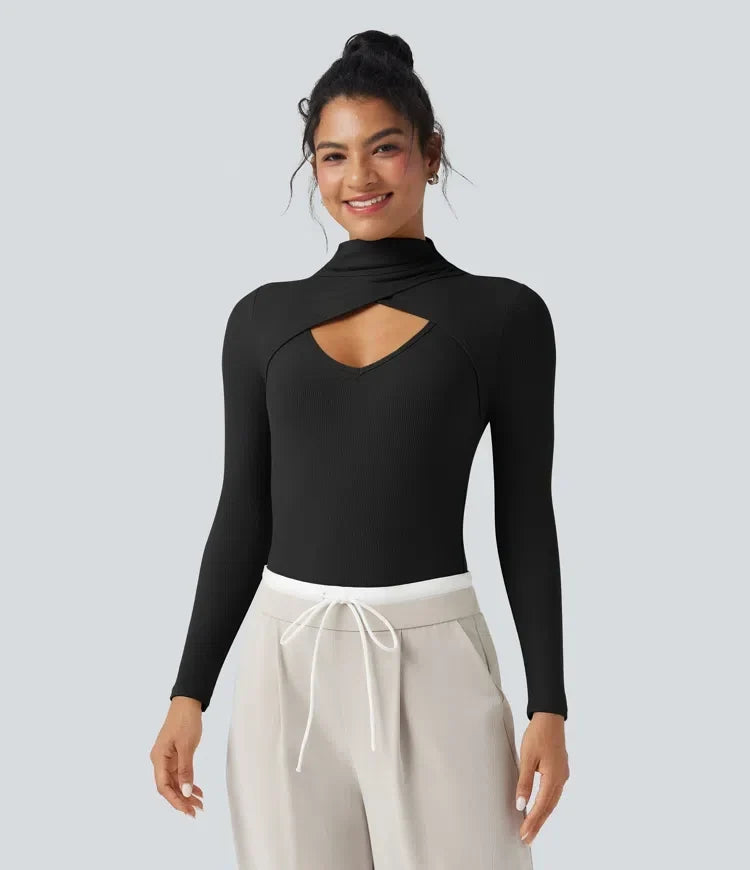 Dam iklädd svart bodysuit med utskurna detaljer och ljusa byxor
