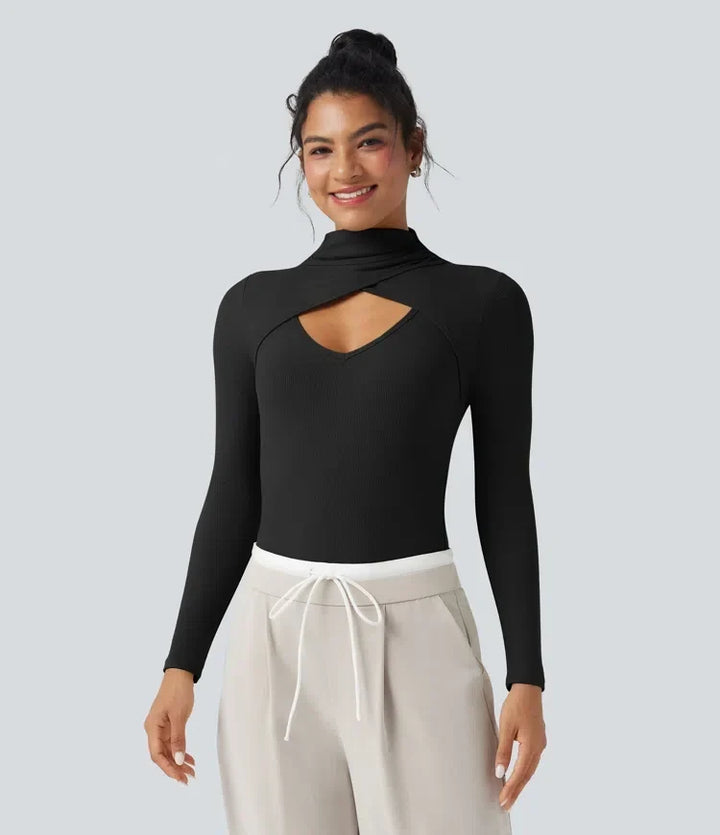 Dam iklädd svart bodysuit med utskurna detaljer och ljusa byxor