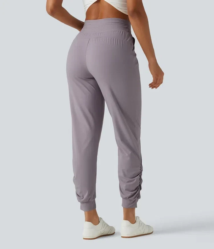 Bakifrån av dam i ljuslila rynkade yogabyxor med fickor och hög midja