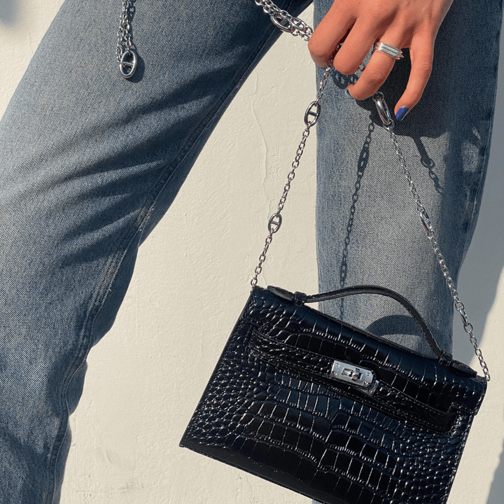 Person som håller i den svarta Fauve axelväskan utomhus mot jeans