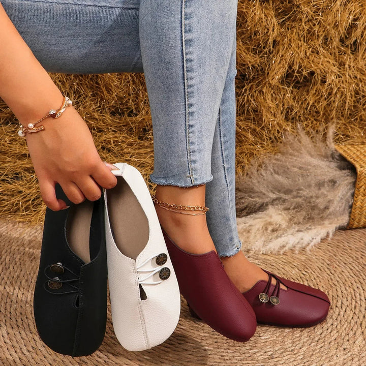 Damloafers i flera färger som hålls upp bredvid jeans
