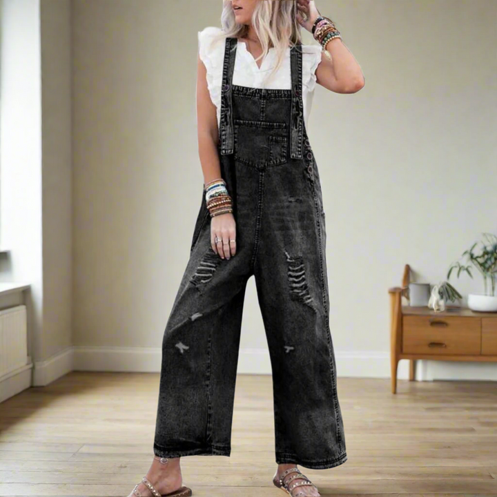 Kvinna i svart vintage jumpsuit med slitdetaljer och sandaler
