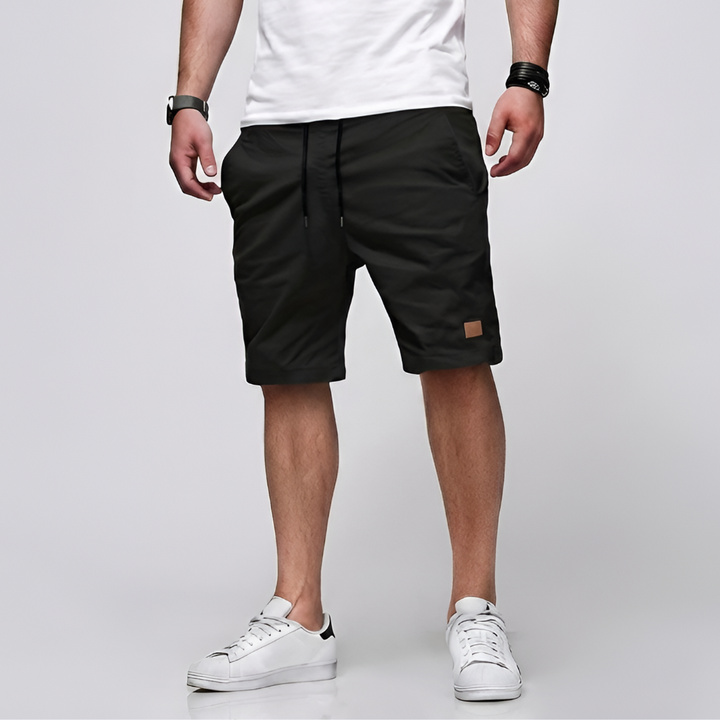 Man i svarta herrshorts med vit t-shirt