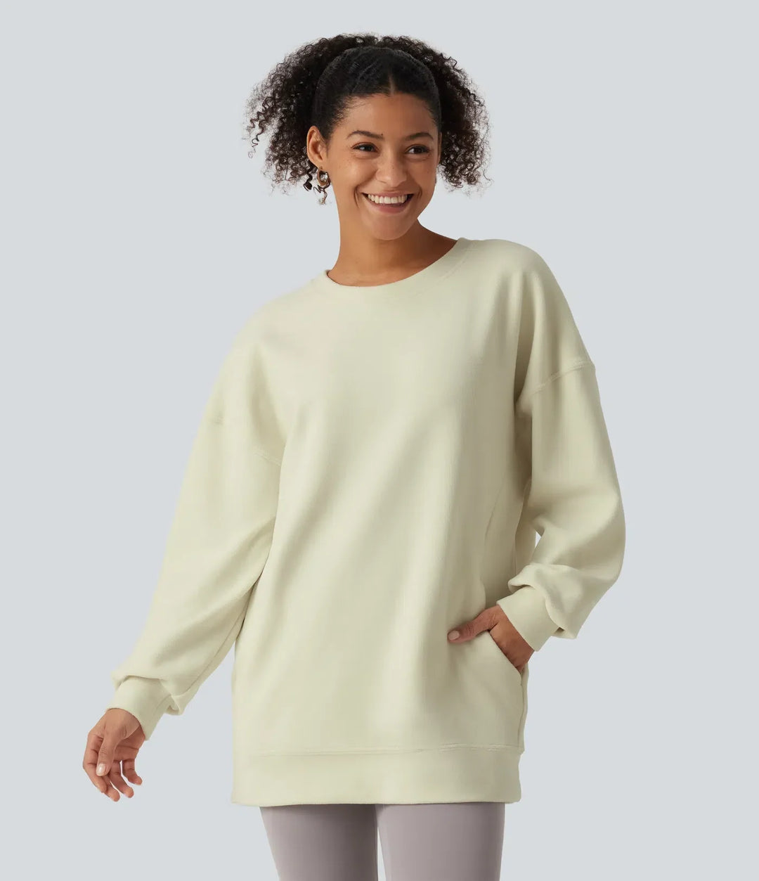 Kvinna som ler iförd en långärmad vardaglig sweatshirt med rund hals och fickor
