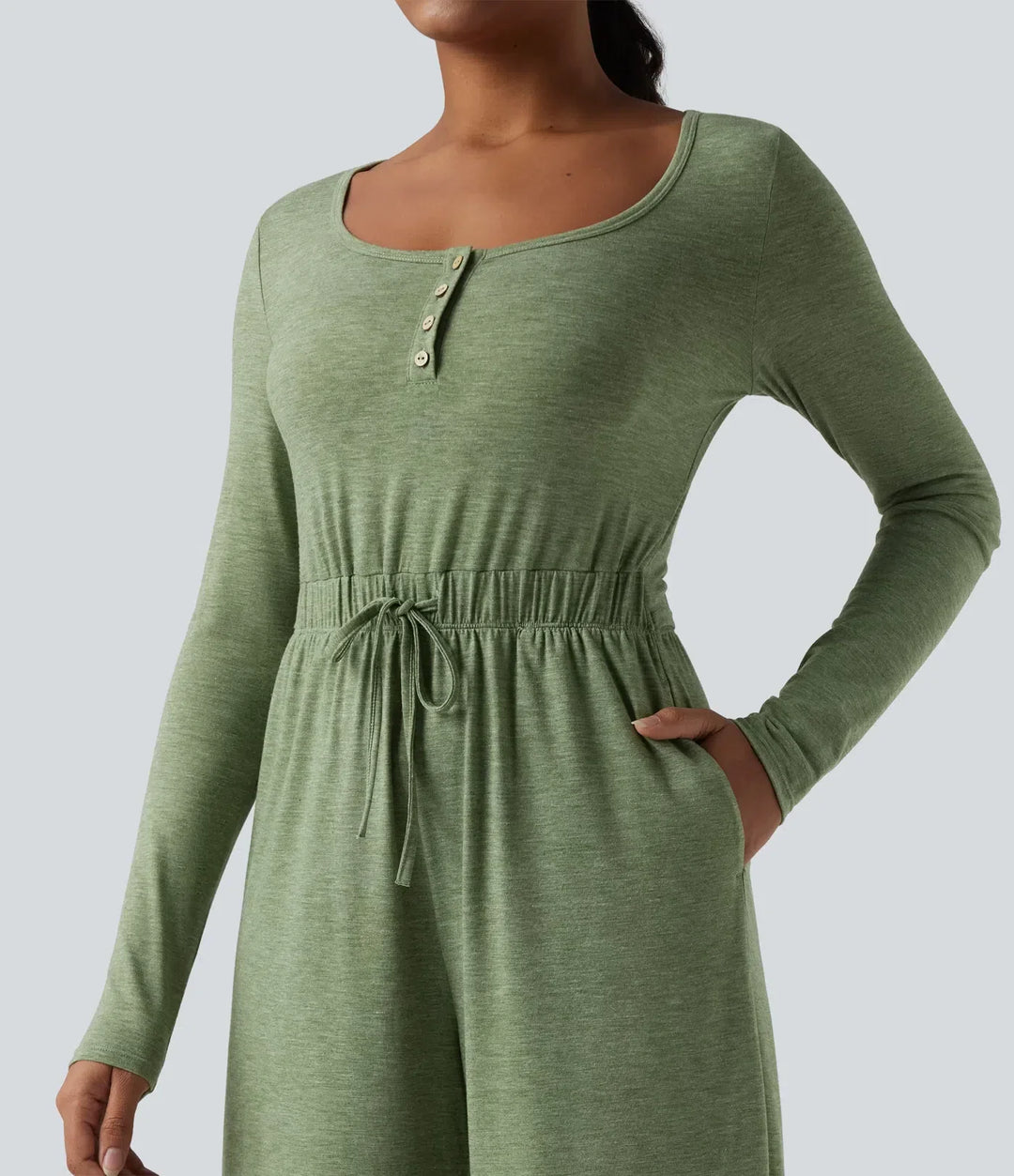 Närbild på praktiska fickor och dragsko på grön vardagsjumpsuit för dam