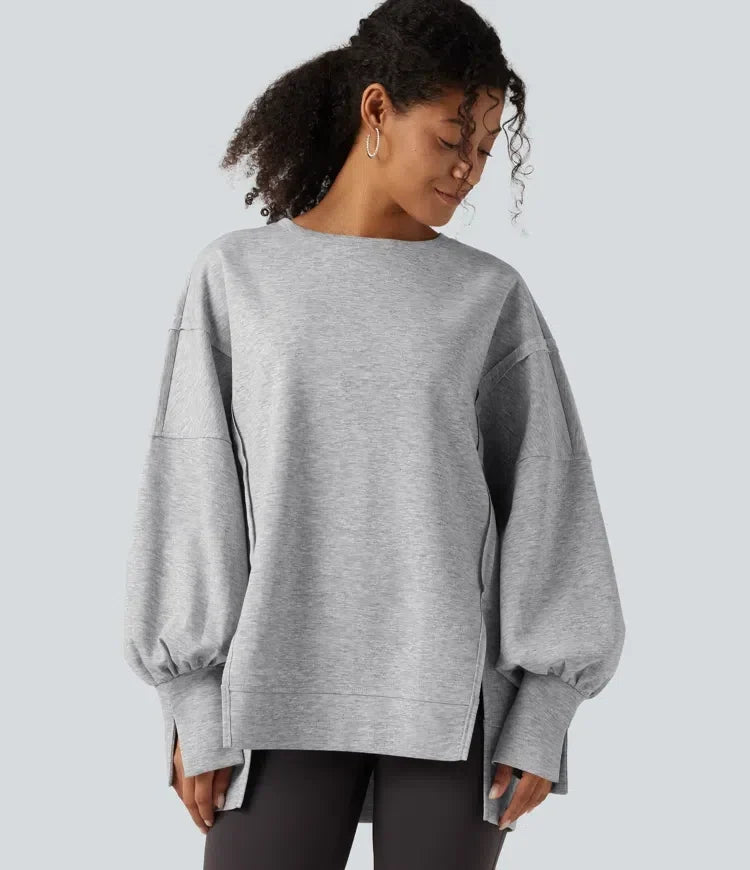 Kvinna som bär grå sweatshirt med rund hals och sidslits framifrån