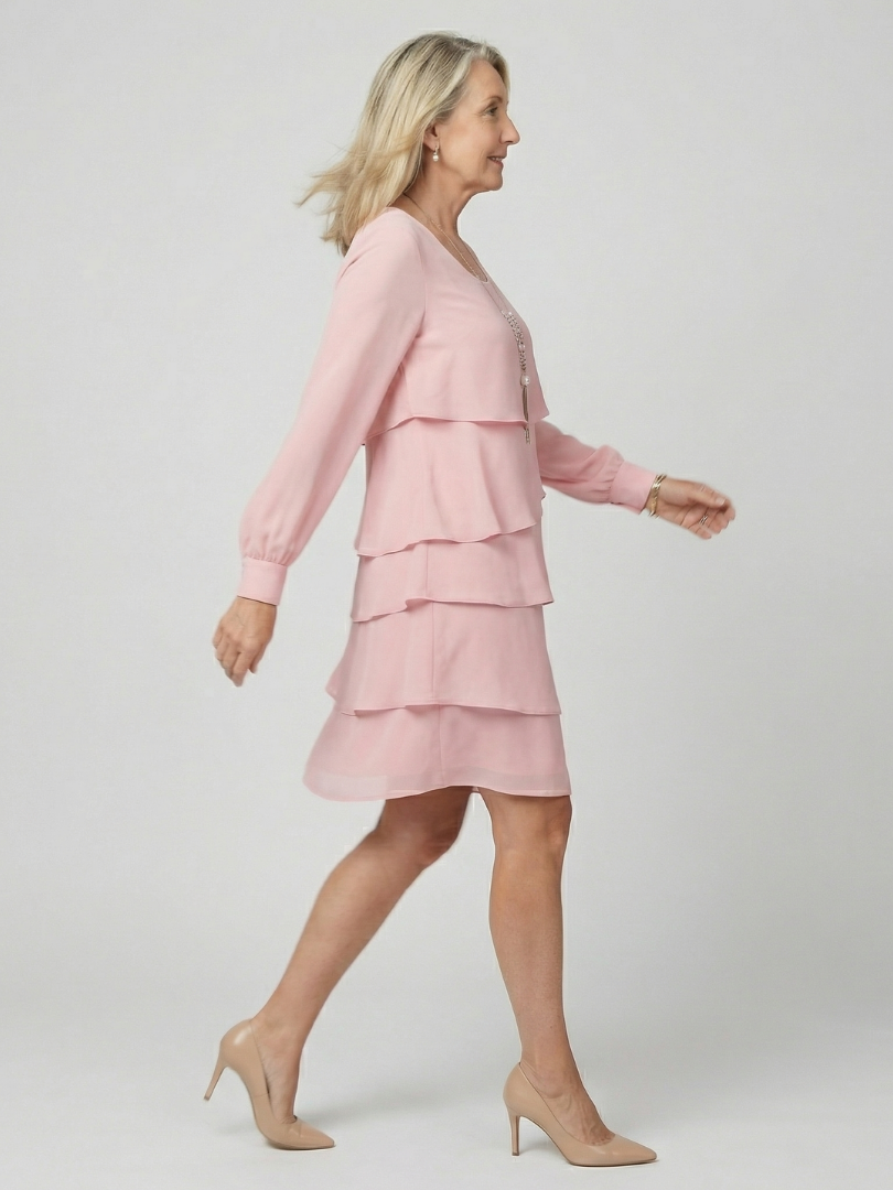 Modell i rosa knälång lagerklänning från sidan