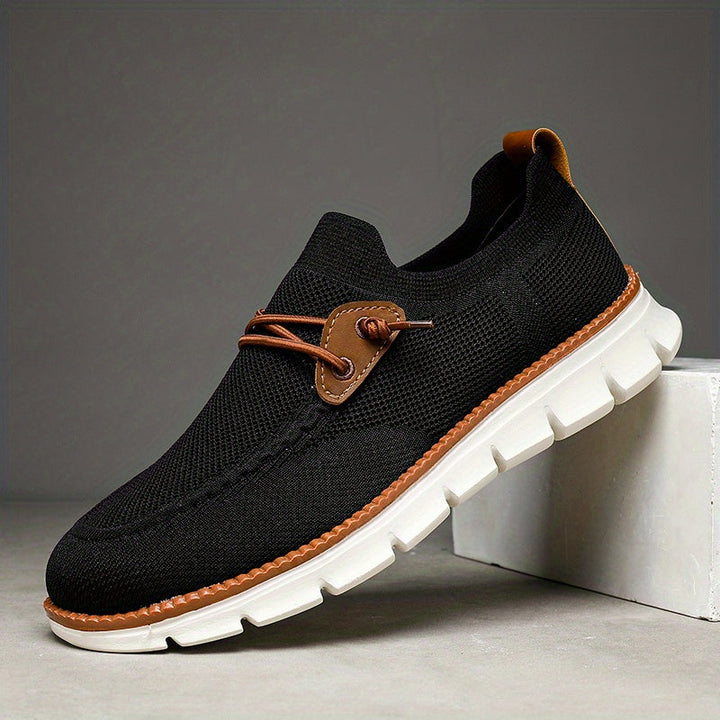 Sida av svarta herr slip-ons med bekväm suldesign och ventilerande ovandel