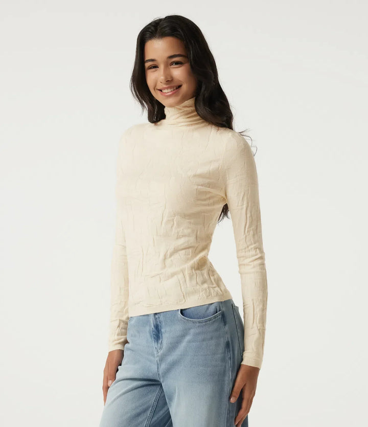 Kvinna som bär en beige tröja i profil med jeans