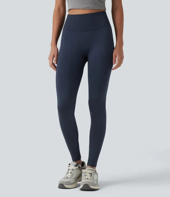 Framifrån av dam i mörka högmidjade yogaleggings med sneakers