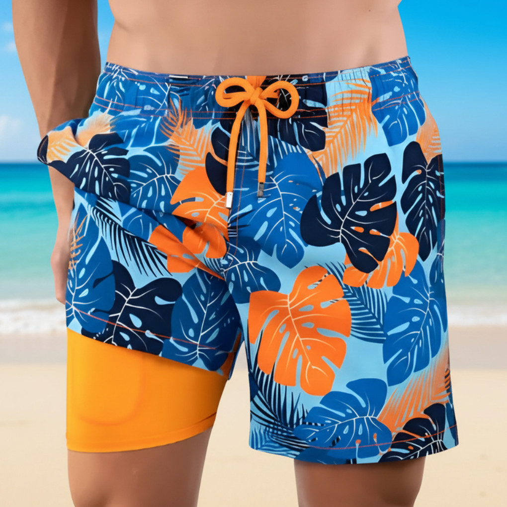 Man i mönstrade simshorts med tropiskt tryck vid stranden