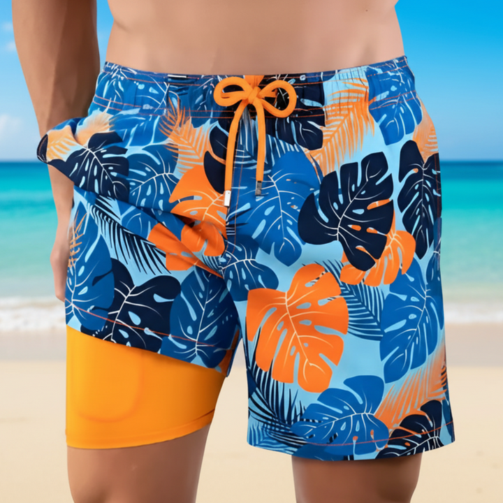 Man i mönstrade simshorts med tropiskt tryck vid stranden