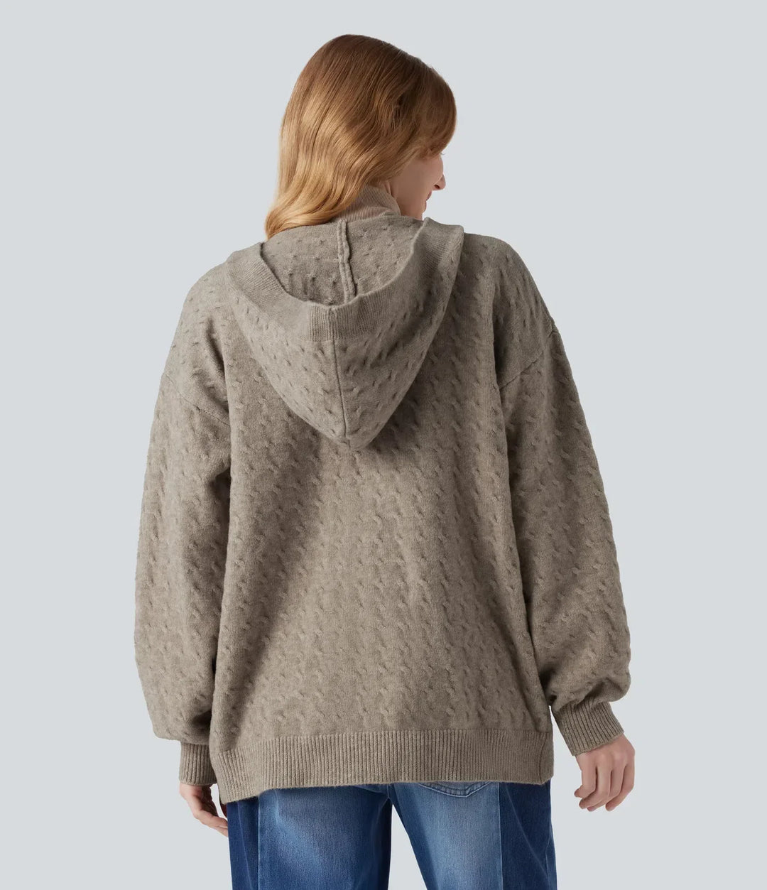 Bakifrån av kvinna i långärmad cardigan med huva