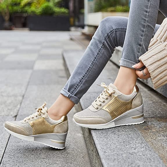Stilrena dam-sneakers med kilklack i guldfärgad nyans matchade med jeans